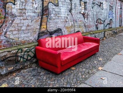 Verlassene, gedumpte, ausgediente, ungewollte rote Ledersofas neben Graffiti-bedeckten Wänden in der Kleinen Rosenthaler Straße, Mitte, Berlin Stockfoto