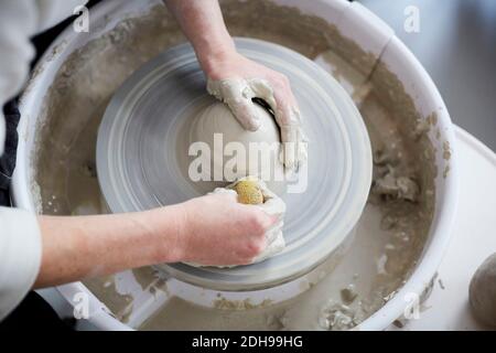 Beschnittene Hände der Frau, die Topf in der Kunstklasse Formen Stockfoto