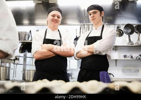 Porträt von lächelnden männlichen Chefstudenten, die Arme gekreuzt stehen Gewerbliche Küche Stockfoto