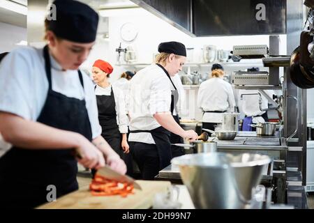 Reifer Lehrer mit Koch Studenten Kochen in der kommerziellen Küche Stockfoto