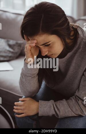 Besorgte Frau, die zu Hause auf dem Sofa sitzt Stockfoto