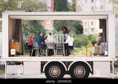Kollegen aus der Wirtschaft diskutieren in einem tragbaren Bürowagen im Park in Stadt Stockfoto