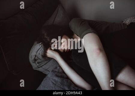 Depressive junge Frau auf Bett liegend Stockfoto