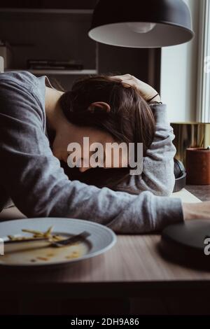 Seitenansicht der traurigen Frau am Tisch Stockfoto
