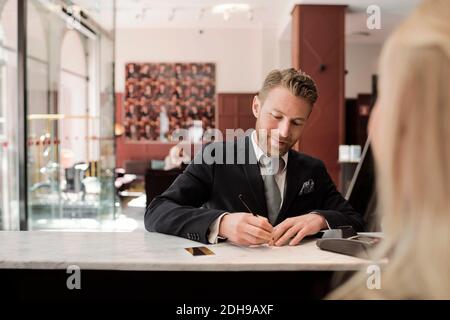 Ein reifer Geschäftsmann zahlt per Kreditkarte an der Hotelrezeption Stockfoto