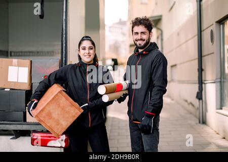 Porträt von selbstbewussten Lieferung Mann und Frau mit Paketen stehen Gegen LKW in der Stadt Stockfoto