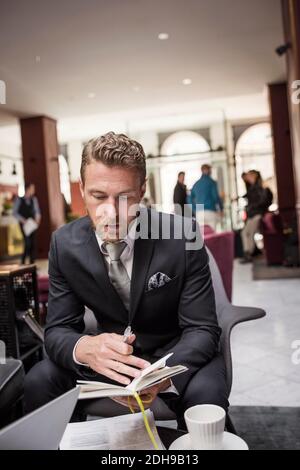 Geschäftsmann, der an der Hotelrezeption sitzt und das Dokument liest Stockfoto