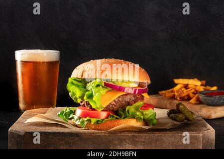Rindfleisch-Burger mit Bier und Pommes frites, Seitenansicht auf dunklem Hintergrund Stockfoto