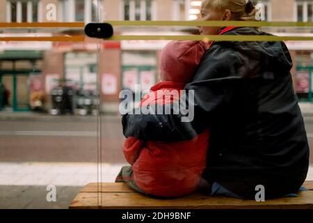 Rückansicht der Großmutter mit Enkel auf der Bank sitzen in Stadt Stockfoto