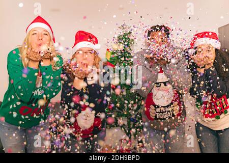 Familie schön weht Konfetti. Verschiedene Generation trägt stilvolle warme Winterkleidung. Weihnachten, Neujahr und Winterkonzept. Fokus auf Zentrum Stockfoto