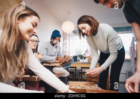 Glückliche junge Freunde essen Pizza in Hochschule Wohnheim Zimmer Stockfoto