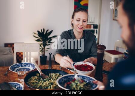 Happy Woman Serving Cherry Tomatoes to man in Teller an Zu Hause Stockfoto