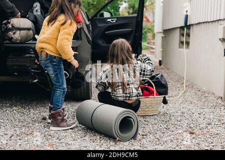 Schwestern laden Gepäck in Elektroauto Kofferraum während der Fahrt Picknick Stockfoto