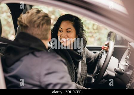 Lächelnde Frau, die beim Fahren des Elektroautos zurückblickt Stockfoto