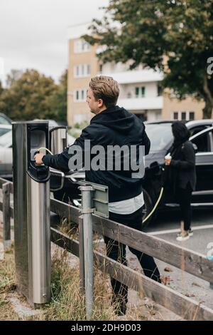 Mann Verbindungskabel an der Ladestation für Elektroautos Stockfoto