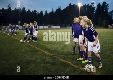 Mädchen stehen mit Fußballbällen auf dem Feld Stockfoto