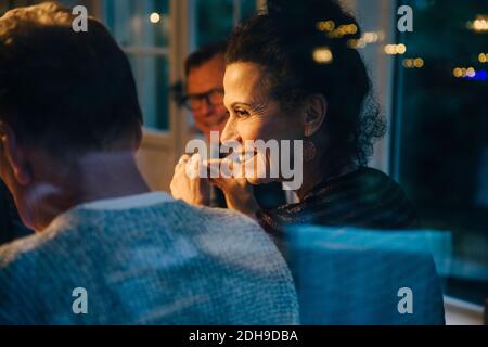 Lächelnde ältere Frau, die den Mann während der Dinner-Party anschaut Stockfoto