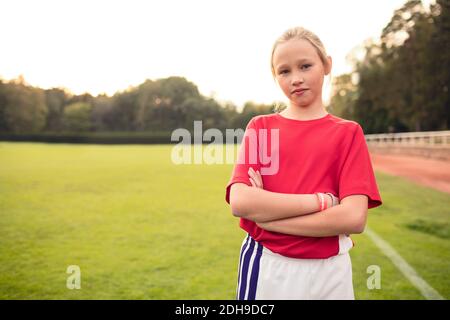 Porträt einer selbstbewussten Fußballspielerin, die mit gekreuzten Armen steht Auf dem Feld Stockfoto