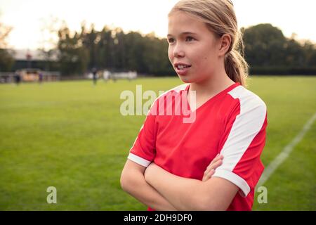 Fußballspielerin steht mit gekreuzten Armen auf dem Spielfeld Stockfoto