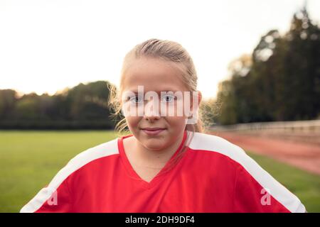 Portrait eines Mädchens in roter Uniform, das auf dem Fußballplatz steht Gegen den Himmel Stockfoto