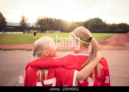 Rückansicht glücklicher Athletinnen, die sich gegenseitig anguckend Stehen auf Fußweg während des Sonnenuntergangs Stockfoto