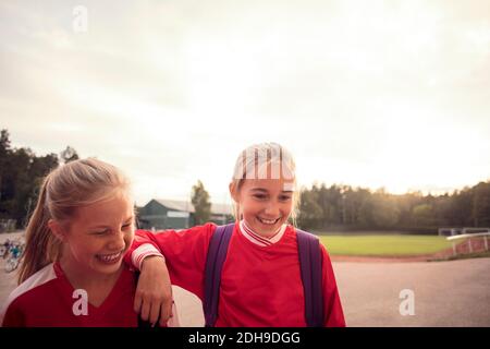 Fröhliche Fußballspielerinnen, die auf Fußwegen gegen den Himmel stehen Stockfoto