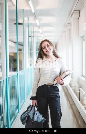 Portrait der lächelnden jungen Studentin im Korridor der Universität Stockfoto