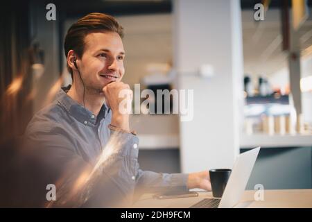Ein nachdenklicher Geschäftsmann, der mit der Hand am Kinn am Schreibtisch sitzt Büro Stockfoto