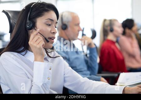 Geschäftsfrau mit Headset bei der Arbeit im Büro Stockfoto