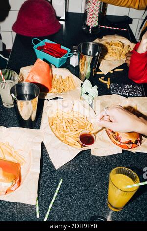 Man hat einen Blick auf Freunde, die Pommes am Tisch essen Im Café Stockfoto