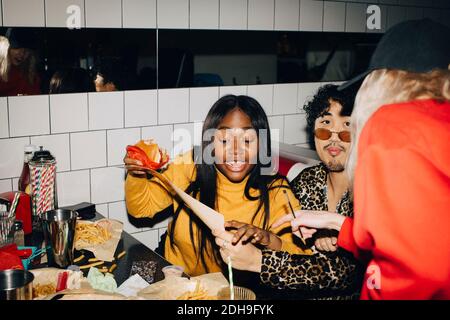 Kellnerin zeigt, während Frau mit Burger Essen von Freund bestellen Im Café Stockfoto