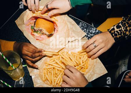 Blick auf Freunde, die Burger und pommes frites essen Am Tisch im Café Stockfoto