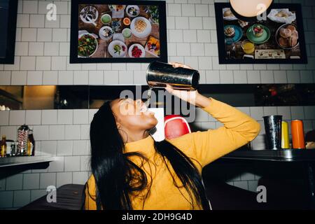 Frau, die Wasser aus Glas im Café trinkt Stockfoto