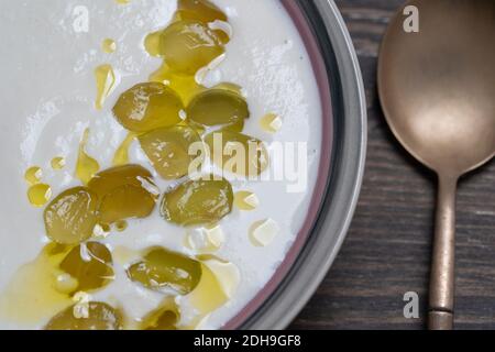 Traditionelles spanisches Gericht, kalte Suppe ajo Blanco oder Ajoblanco aus Knoblauch, Mandeln, Weißweinessig, Olivenöl und grünen Trauben in einer Schüssel mit einem Löffel Stockfoto