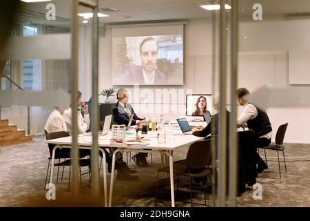 Führungskräfte, die in Meetings während einer Webkonferenz diskutieren, durchgesehen Glas im Büro Stockfoto