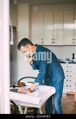 Mann, der von zu Hause aus mit Kollegen telefoniert Stockfoto