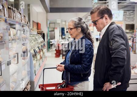 Reifes Paar beim Blick auf Lebensmittelschrank im Supermarkt Stockfoto