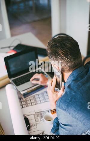 Beschäftigt Mann am Telefon mit Laptop zu Hause Stockfoto