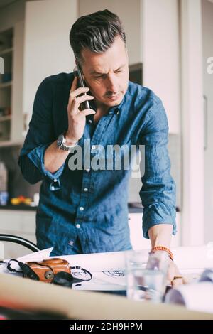 Mann im Büro zu Hause im Telefongespräch Stockfoto