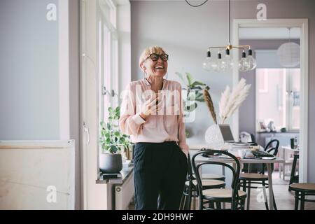Frau, die am Telefon lacht zu Hause Stockfoto