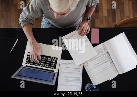 Direkt über dem Bild eines älteren Mannes mit Rechnungen über Laptop Am Tisch Stockfoto