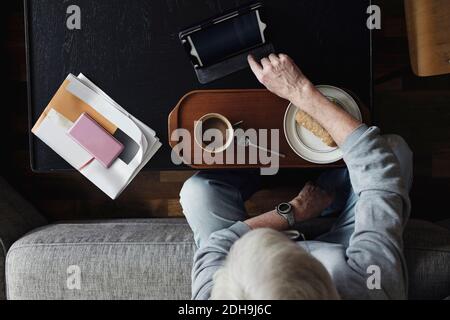 Direkt über Schuss von Senior Mann mit digitalen Tablet, während Frühstück zu Hause Stockfoto