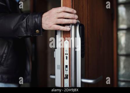 Beschnittenes Bild von älteren Mann trägt Lederjacke Öffnung Holz Tür Stockfoto