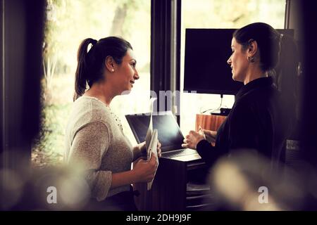 Weibliche Besitzerin, die mit dem Kunden über Bestellung spricht, während sie im Hotel steht Café Stockfoto