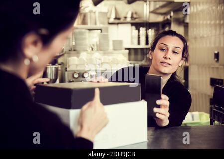 Besitzer mit Telefon, während Mitarbeiter auf Modembox zeigt Café Stockfoto