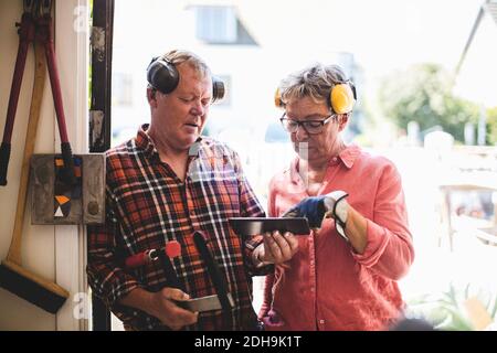 Seniorenpaar diskutiert über digitale Tablet während der Werkstatt stehen Eingang Stockfoto