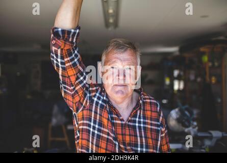 Porträt eines selbstbewussten älteren Mannes, der in der Werkstatt steht Stockfoto