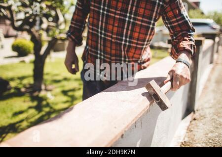 Mittelteil eines leitenden Mannes, der die Außenwand kontrolliert Stockfoto