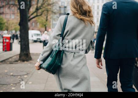 Rückansicht einer Geschäftsfrau mit Handtasche, die von einem Kollegen in die Hand geht Stadt Stockfoto