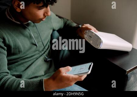 Teenager hält Router beim Überprüfen der Wi-Fi-Verbindung auf dem Handy Telefon zu Hause Stockfoto